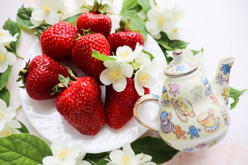 ripe strawberries on a white plate and jasmine flowers. still life