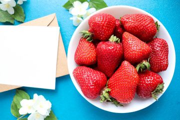 ripe strawberries on a white plate and jasmine flowers. still life