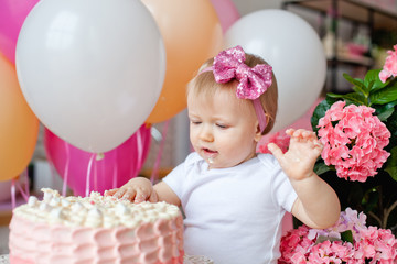 little girl on the table with a birthday cake and balloons