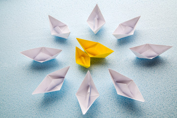 Two yellow paper boats surrounded by many large white boats. - 352233604