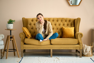 Obraz premium Calm mood weekend. Girl on the couch relaxing in living room, thinking and recalling pleasant moments