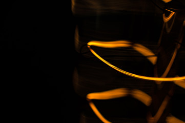Macro shot of glowing swirl on light bulb on black background with copy space