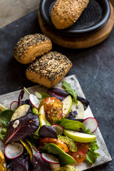 delicious tomato and guacamole lettuce salad, with green apple and radish on dark background