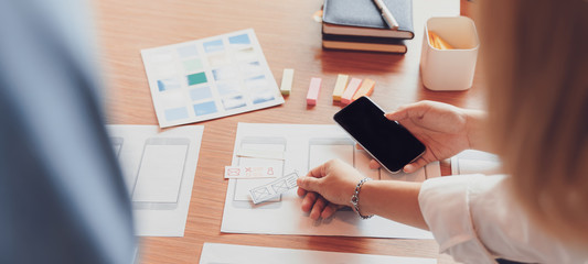 Cropped shot of creative UX UI designers team designing, Developing mobile application from prototypes and wireframe layout. Mobile application developer workplace concept.