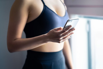 Fit woman using phone. Gym workout and exercise with sport tracker mobile app in smartphone. Athlete, fitness model, health expert, personal trainer or professional nutritionist. Training lifestyle.