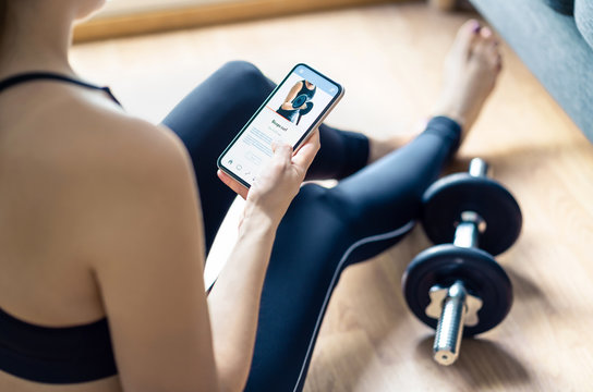 Home gym workout with online exercise app in phone. Fit woman watching training tutorial video or using digital personal trainer with smartphone. Internet coach. Sport routine or class in cellphone.