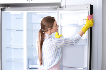 Fototapeta na wymiar Woman in rubber gloves cleaning refrigerator at home
