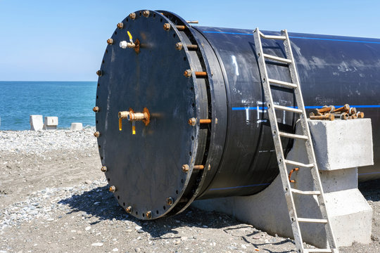 A locked large plastic pipeline on the coast with blue sea background