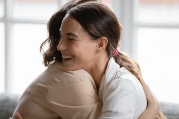 Smiling millennial girl child hug mature mother make peace reconcile after fight, happy thankful adult grownup daughter and middle-aged mom embrace, show love and gratitude in family relationships