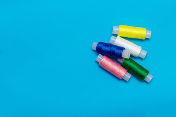 white, blue, green, pink, yellow thread and turquoise ribbon on a blue background, copy space, top view