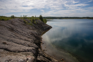 Flooded kaolin clay open pit quarry with blue water lake