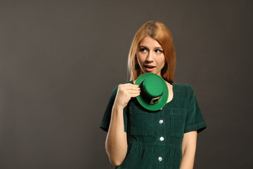 Young woman with green leprechaun hat on grey background, space for text. St. Patrick's Day...