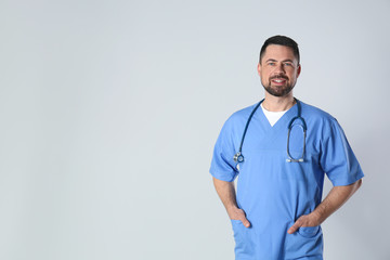 Portrait of mature doctor against light background