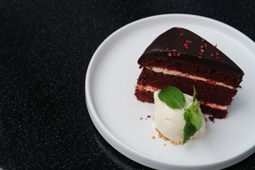 close up one slice of chocolate cake and ice cream in white plate on black table