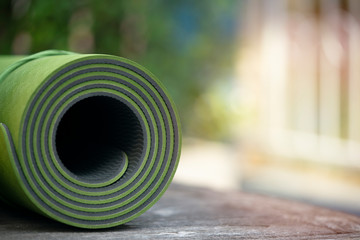 close up of green yoga mat on the table, sport and healthy concept