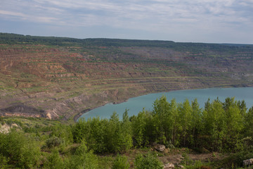 Abandoned coal ore quarry open pit flooded with blue water