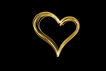 Long exposure photograph of neon gold colour in an abstract heart shape outline, parallel lines...
