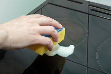 Close-up of a female hand rubbing a stain from a stove