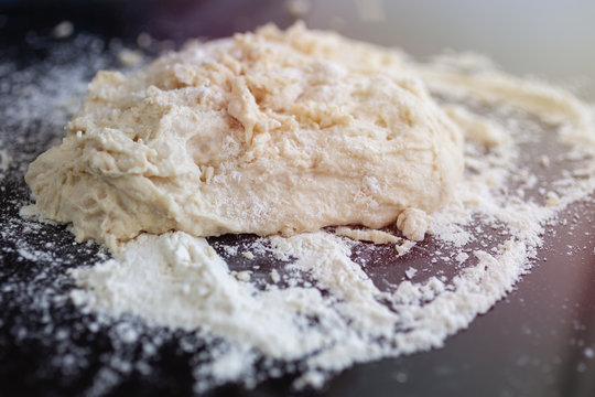 Close up background of kneaded dough for bread, pasta or pizza on black table
