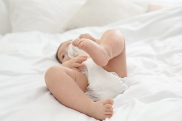 Obraz na płótnie Canvas Cute little baby in diaper on bed