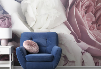 Comfortable armchair near wall with floral wallpaper, space for text. Stylish living room interior