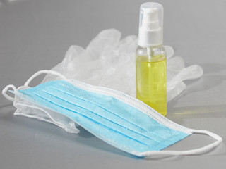 Tube with sanitizer, medical gloves and mask on a gray background