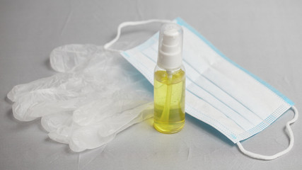 Tube with sanitizer, medical gloves and mask on a gray background