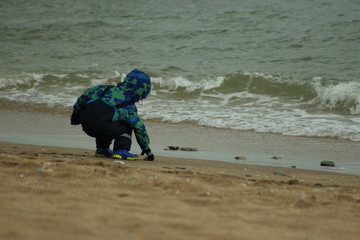 child by the sea
children games
little boy raises a stone 