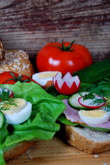 sandwich with lettuce, ham and boiled egg rings, radish and dill