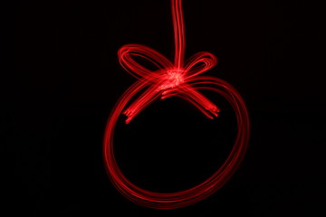 Long exposure photograph of neon red colour in a Christmas bauble shape outline, parallel lines...