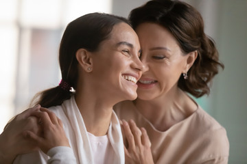 Loving mature 60s mother hug cuddle happy millennial girl child enjoy tender intimate close family moment at home, caring middle-aged mom embrace grownup adult daughter relaxing together