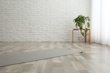 Unrolled grey yoga mat on floor in room - Powered by Adobe
