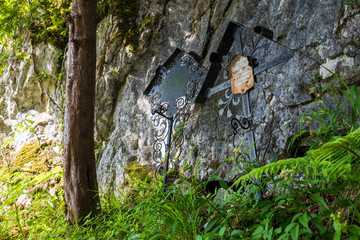 View of two ancient overgrown tombs with forged crosses at a rock face at the cemetery of Hallstatt, Salzkammergut region, O&Ouml;, Austria