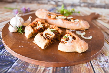 würzige türkische pide mit Fetakäse Zwiebeln Knoblauch auf einem Schneidebrett aus Holz 