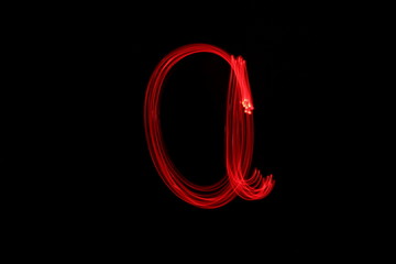 Long exposure photograph of the letter a in neon red colour fairy lights against a black...
