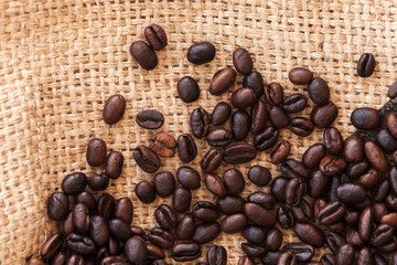 Roasted coffee beans are on jute bag fabric. Flat lay