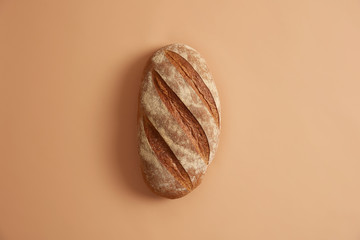 Freshly baked homemade long loaf isolated over beige background. Different ingredients such as flour, salt and yeast needed to prepare white wheat bread. Baking concept. Necessary product for eating