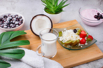 Cottage cheese with fresh summer berries and coconut in a bowl, top view of the table