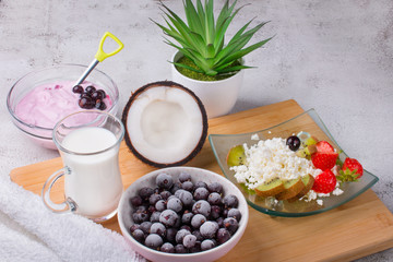 Cottage cheese with fresh summer berries and coconut in a bowl, top view of the table