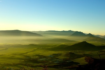 sunset over a green valley with some fog