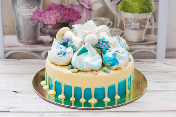 Blue cake with melted white chocolate, meringues and fondant crown. Rustic wooden background.