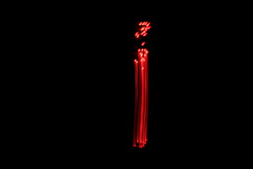 Long exposure photograph of the letter i in neon red colour fairy lights against a black...