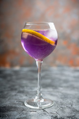 Colorful cocktail with lemon and lavender liqueur in wineglass on the rustic background. Selective focus. Shallow depth of field.
