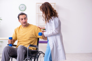 Young male patient in wheel-chair doing physical exercises