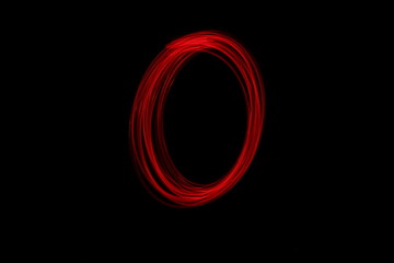 Long exposure photograph of the letter o in neon red colour fairy lights against a black...