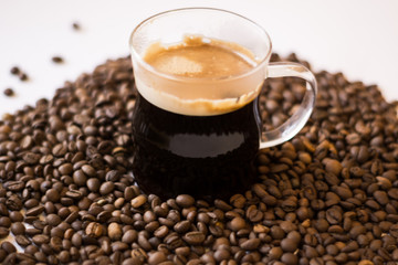 A lot of roasted coffee beans on a white background a cup of marshmallows foam