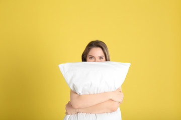 Fototapeta premium Young woman with pillow on yellow background