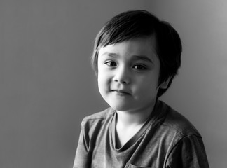 Black and white portrait of healthy kid, Happy child looking at camera with smiling face, Candid shot cute little boy relaxing stay at home during covid lock down.Positive children concept