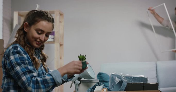 Young caucasian family is moving to a new house, designing their wall decoration, guy hanging a frame to instructions of girl - new life, mortgage concept 4k footage