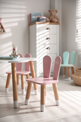 Small table and chairs with bunny ears in children's room interior
